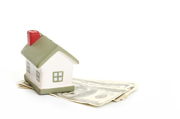 Model of a house lying on some banknotes