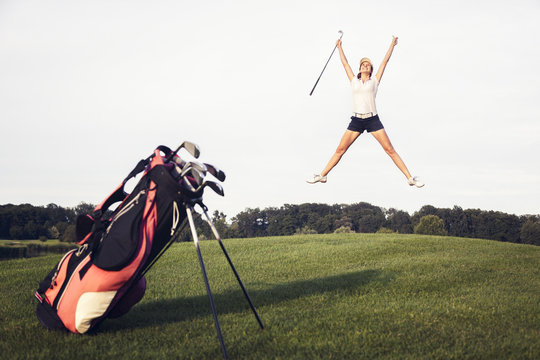 Happy golf player jumping on golf course.