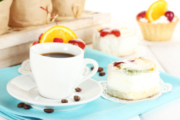 cup of coffee and sweet cakes with fruits on wooden table