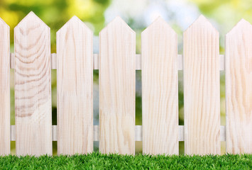 wooden fence and green grass on bright background.