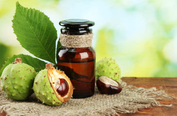 medicine bottle with chestnuts and leaves, on green background