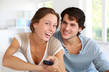 Fototapeta premium Couple sitting in sofa with remote control in hands