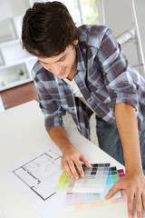 Cheerful young man looking at colours sample for new home