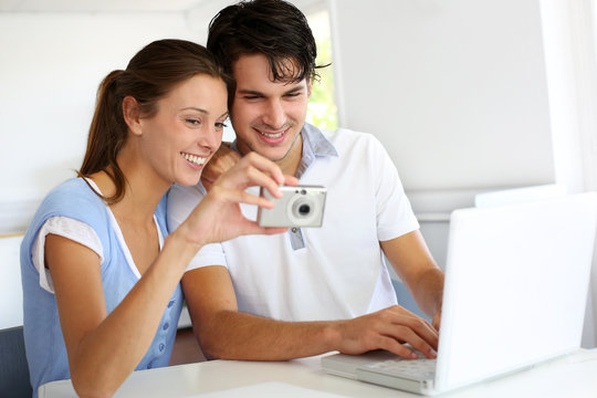 Couple at home uploading photographies on internet