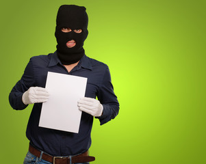 Man wearing a robber mask showing a blank paper