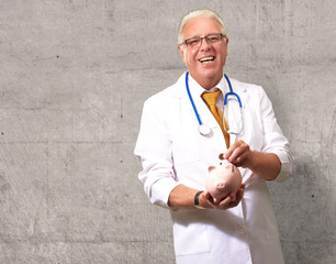 Male Doctor Putting Coins In A Piggy Bank