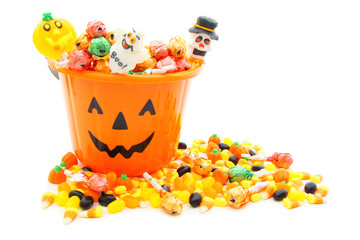 Jack-o-lantern candy pail with a pile of Halloween candy