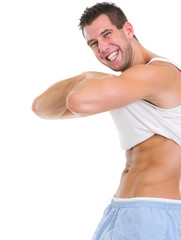 Happy muscular man raising shirt to show abdominal muscles