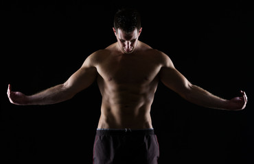 Fototapeta na wymiar Strong muscular man posing on black