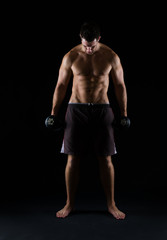 Fototapeta na wymiar Strong muscular man holding dumbbell on black
