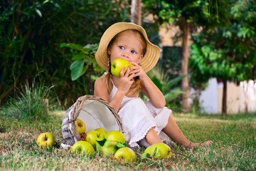 девочка кусает яблока на полянке