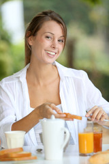 Young woman having bread for breakfast