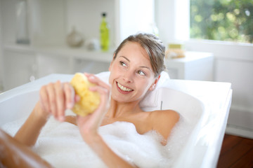 Beautiful woman using bath sponge