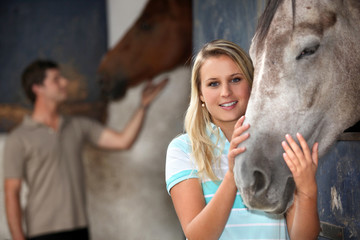 Young woman stroking her horse