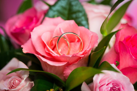 Two wedding rings on rose in bridal bouquet