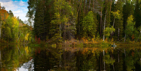 fisher in boat is on the forest lake in autumn