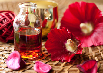 Obraz na płótnie Canvas Olejek do aromaterapii i czerwone kwiaty