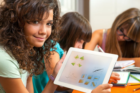 Cute girl showing homework on tablet.