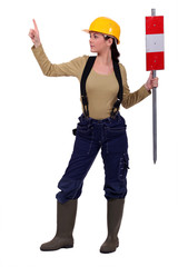 female helmeted worker holding construction sign