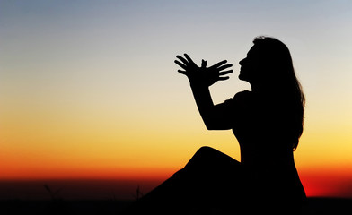 Girl at sunset, hands symbolize the bird