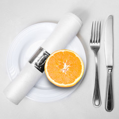 fresh orange on plate served with knife, fork and napkin