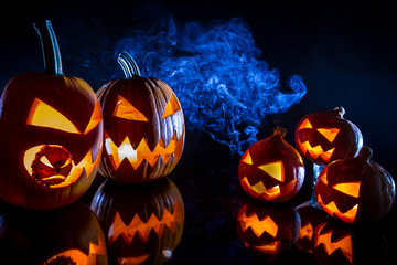 Small and large pumpkins for Halloween with candles on a black b