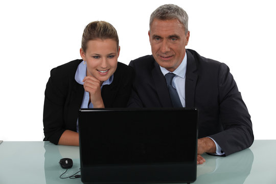 businessman and businesswoman smiling in front of the laptop