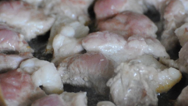 Turning over frying pork meat on pan