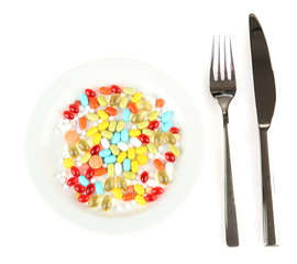 a lot of pills in a plate with knife and fork isolated on white