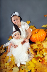 Cute little girls with pumpkin and autumn leaves