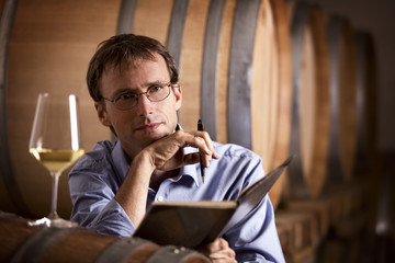 Wine producer contemplating in cellar.