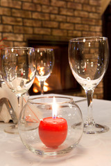 burning candle on the served table against a fireplace