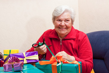 seniorin lächelt und packt geschenke ein oder aus