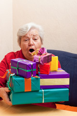 seniorin sitzt auf der couch und nimmt oder gibt stapel geschenk