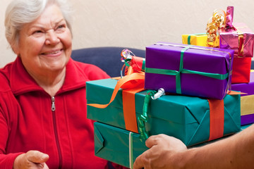 Seniorin sitzt und bekommt oder gibt viele geschenke 2