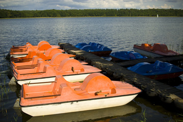 Pedal boats moored at a marina on the lake .