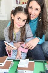 Mother and daughter sat by scale model of housing