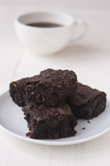 Chocolate brownies and a cup of coffee on a black background