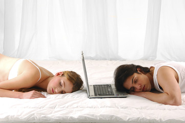 Couple lying in bed sleeping with laptop