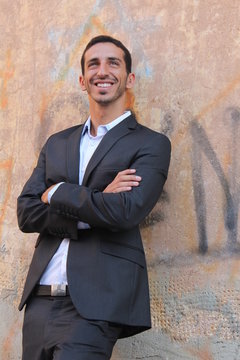 Middle-east businessman standing near a wall and smiling