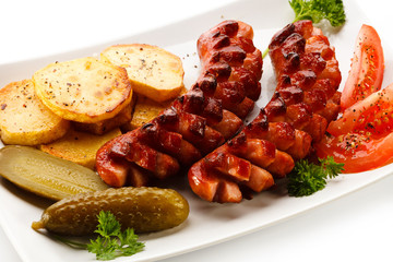 Grilled sausages, baked potatoes and vegetables