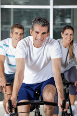 Fototapeta premium Three People On Exercise Bikes