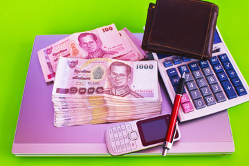 close up of 1000 baht banknotes and calculator on note book