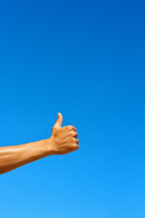 Isolated thumbs up against blue sky
