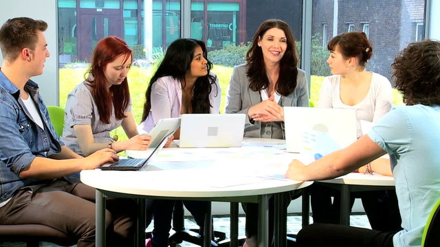 Multi ethnic students and teacher researching on computers