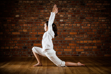 Girl exercising yoga against brick wall