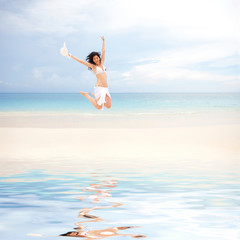 happy young woman jumping on the beach of sea