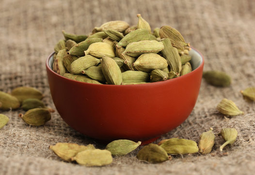 Green cardamon in ceramical bowl on canvas background close-up