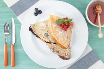 crespelle con marmellata cioccolata miele e frutta su piatto