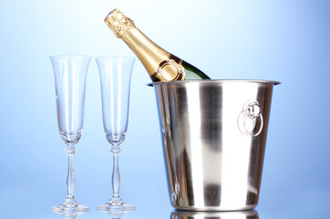 Champagne bottle in bucket with ice and glasses